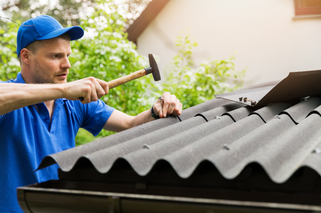 man hammering nail into roof for Low Sloped Roofing Athens GA